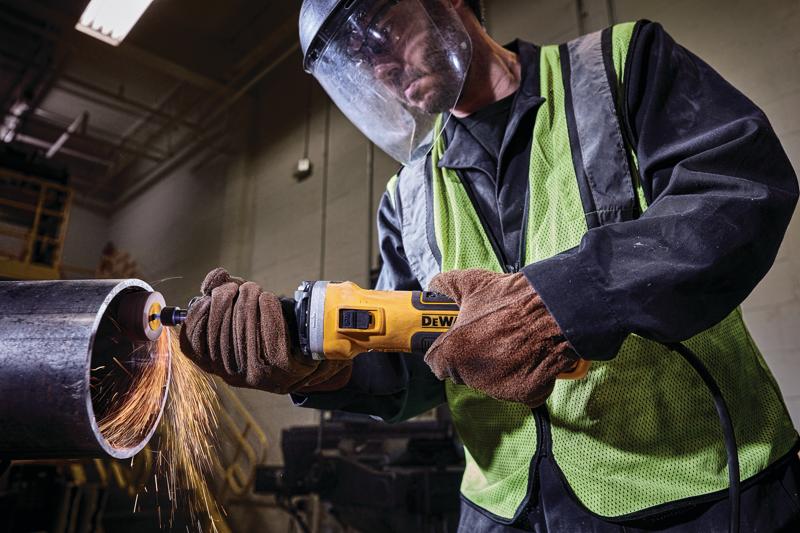 Arbeiter benutzt DEWALT Winkelschleifer zum Schneiden von Metallrohr, Funken fliegen, trägt Schutzkleidung.